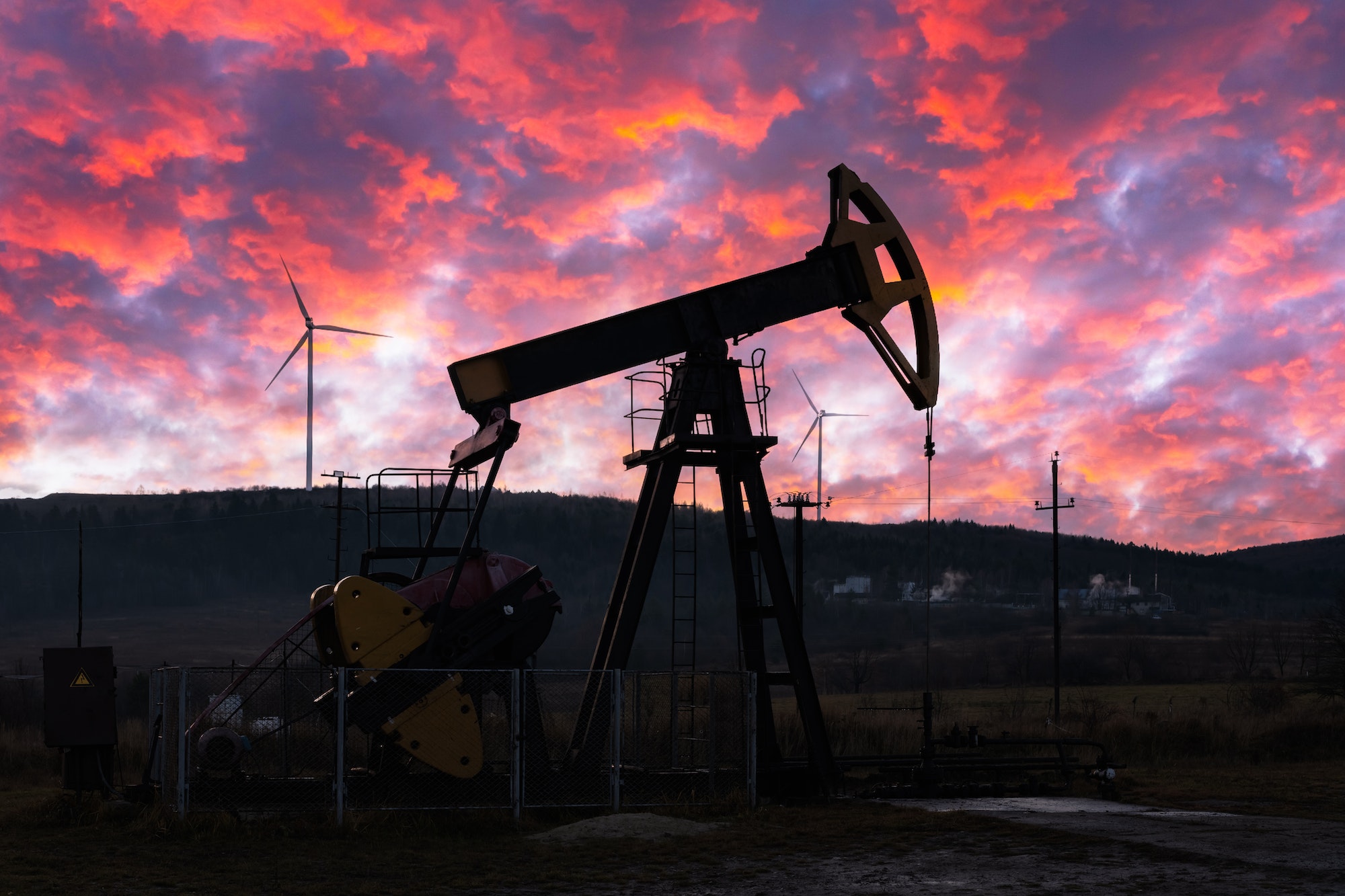 Oil pump and wind turbines against incredible purple sunset sky